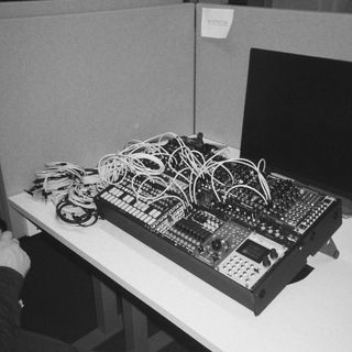 An old school black and white picture of a 208hp patched eurorack case, sittingg on a desk.