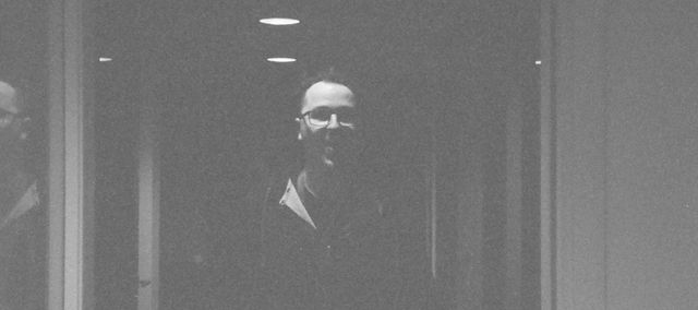 A blurry black and white picture of myself, standing in a corridor.